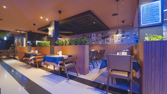 Bar seating in blue light with planters and a lit menu board