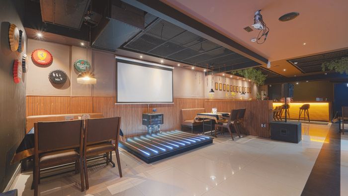 Bar lounge with a projector screen and a small lit stage