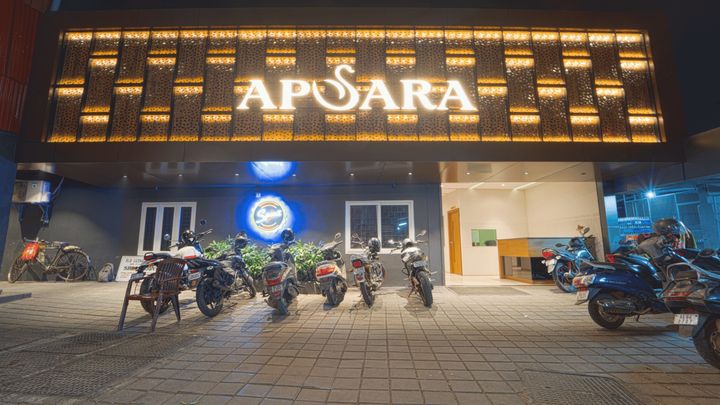 The lit timber lattice and Apsara sign above the hotel entrance at night
