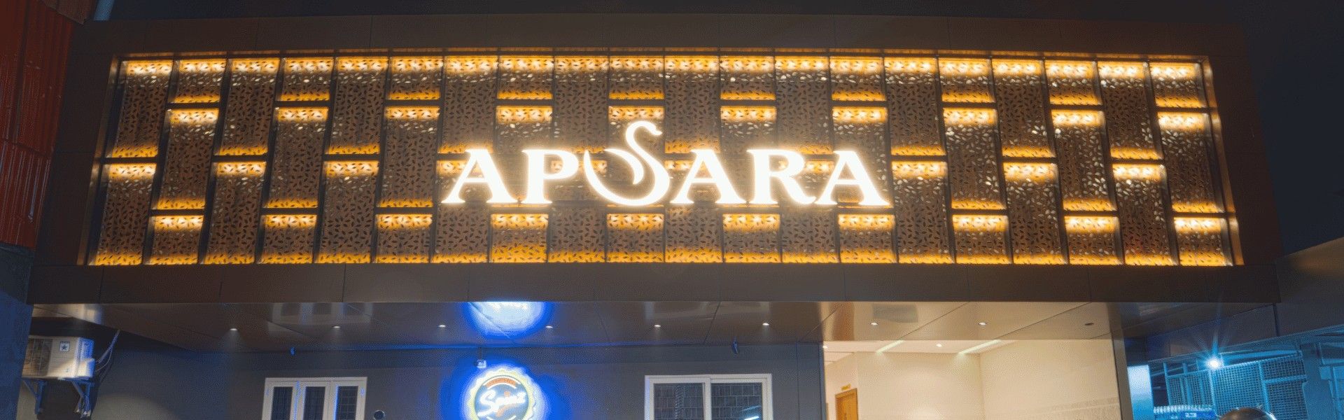 The Apsara sign set in the lit timber lattice above the hotel entrance