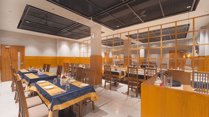 Restaurant tables laid with navy cloths and gold runners