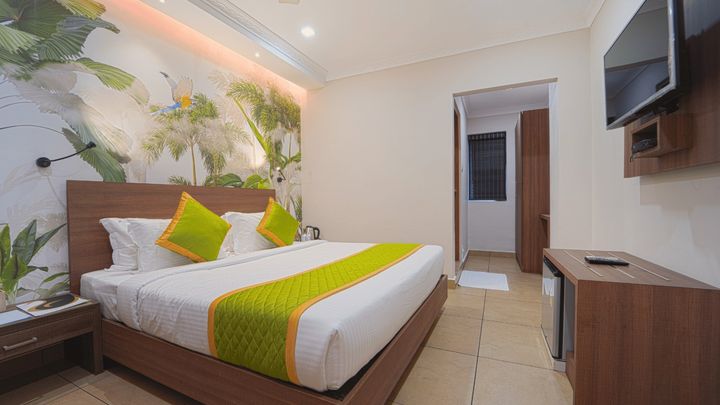 Room with a king bed and a tropical leaf mural behind the headboard