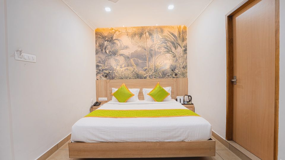 Room with a double bed, a leaf mural and a wooden door