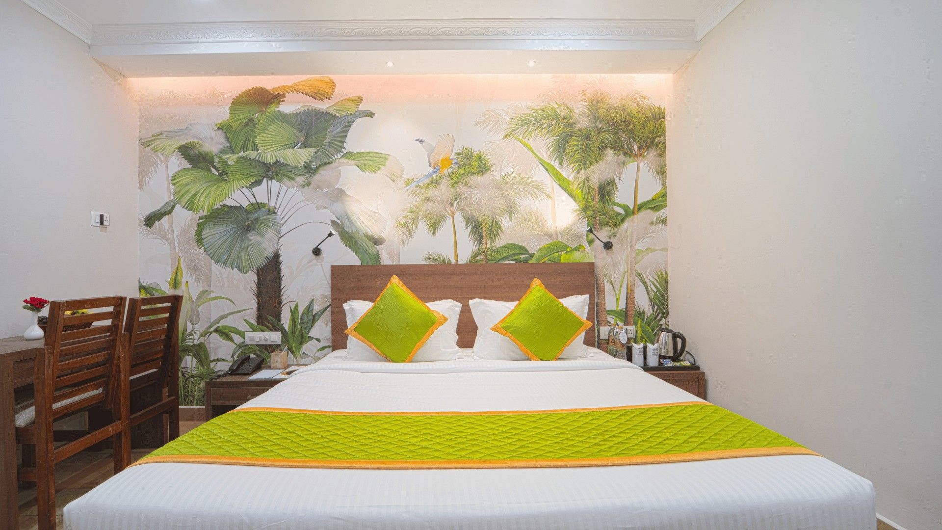 King bed with lime-green cushions under a leaf mural